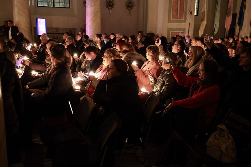 People in the public holding lit candles during the concert